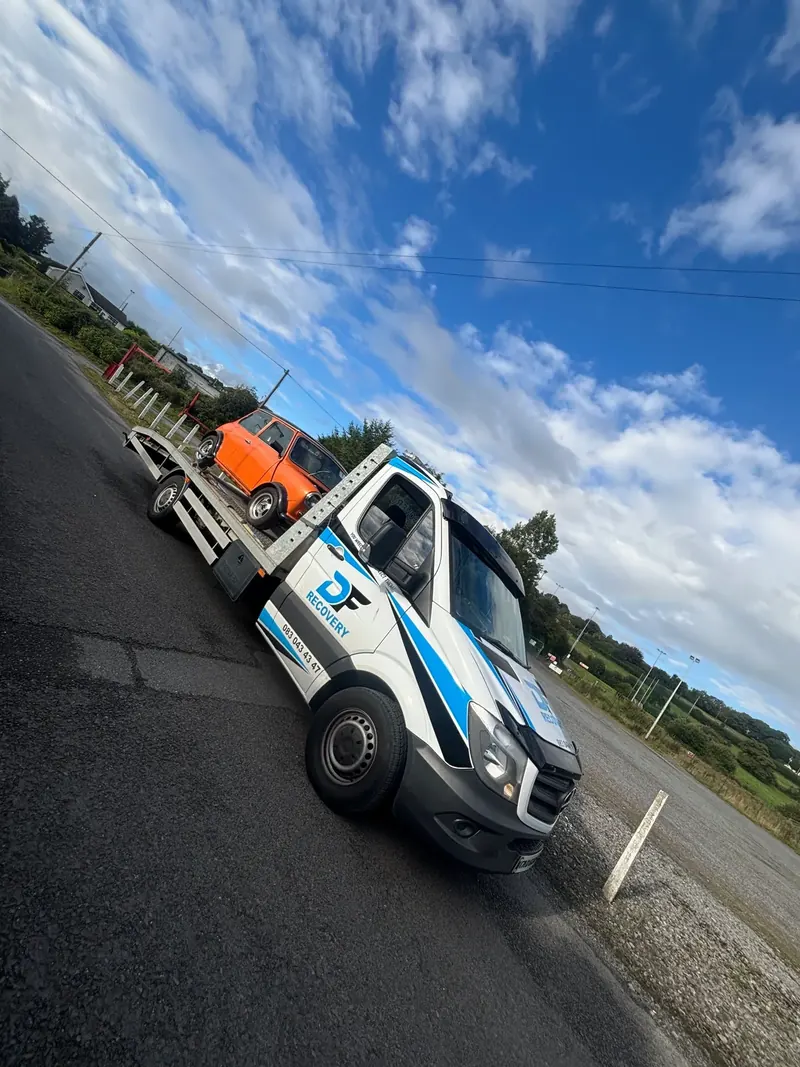 DF Recovery truck transporting a classic orange Mini on a country road