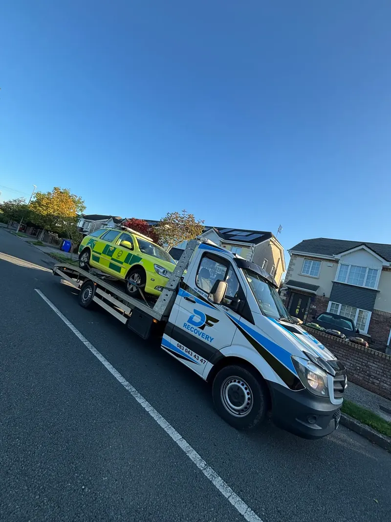 DF Recovery truck carrying a high-visibility response car under a clear sky